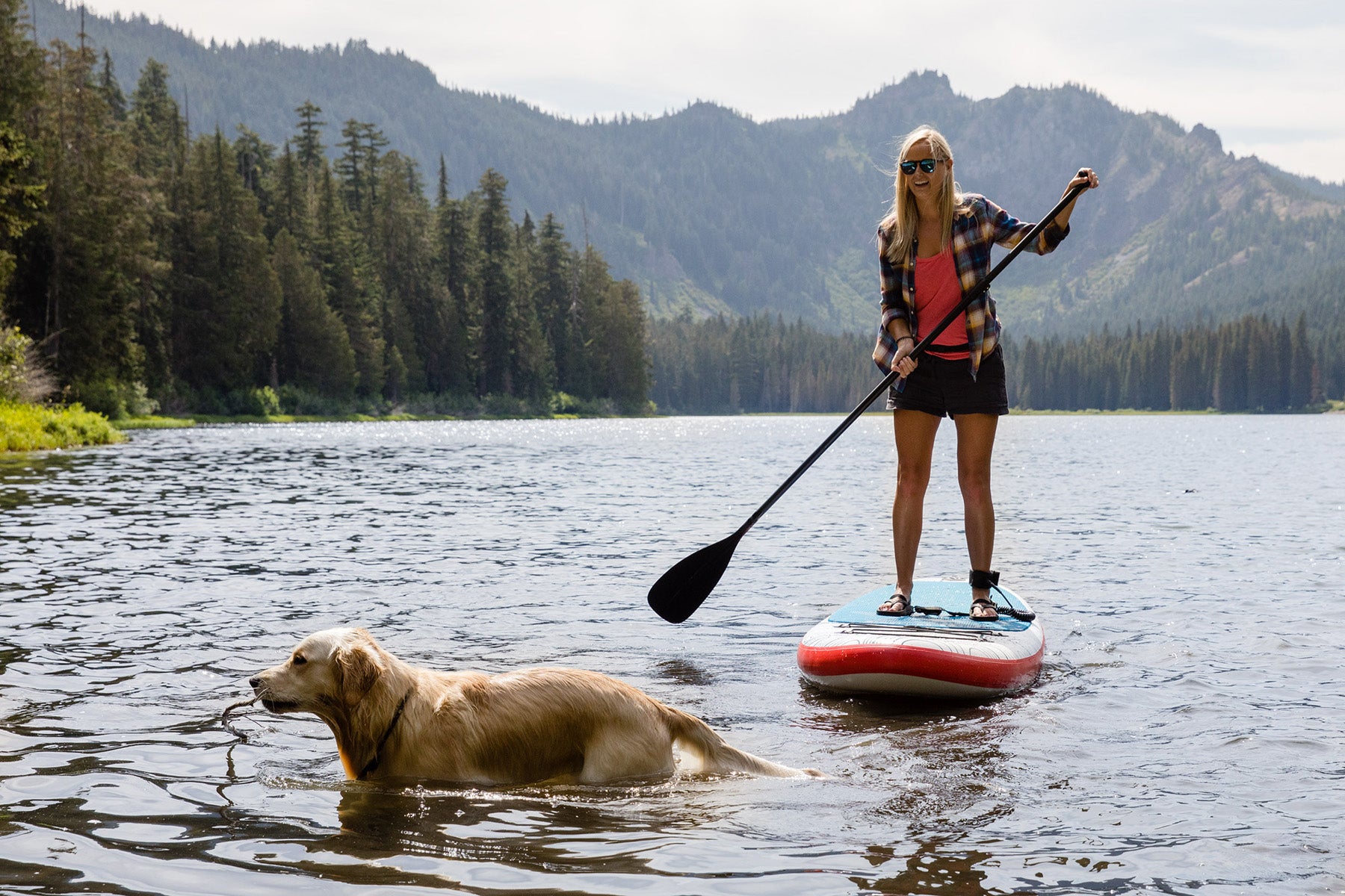 Woman and dog playing on Caspian inflatable stand up paddleboard from Stand on Liquid 