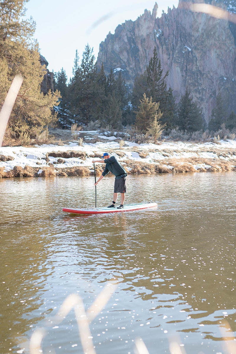 Man paddling on inflatable stand up paddleboard by Stand on Liquid at Smith Rock State Park